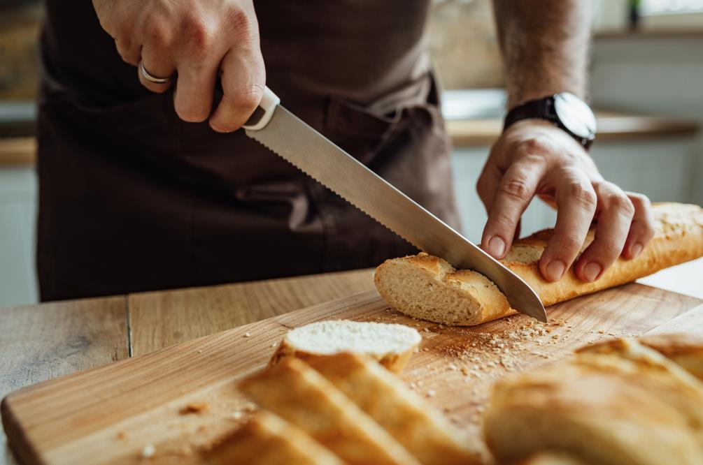 Close-up of man cutting bread in the kitchen