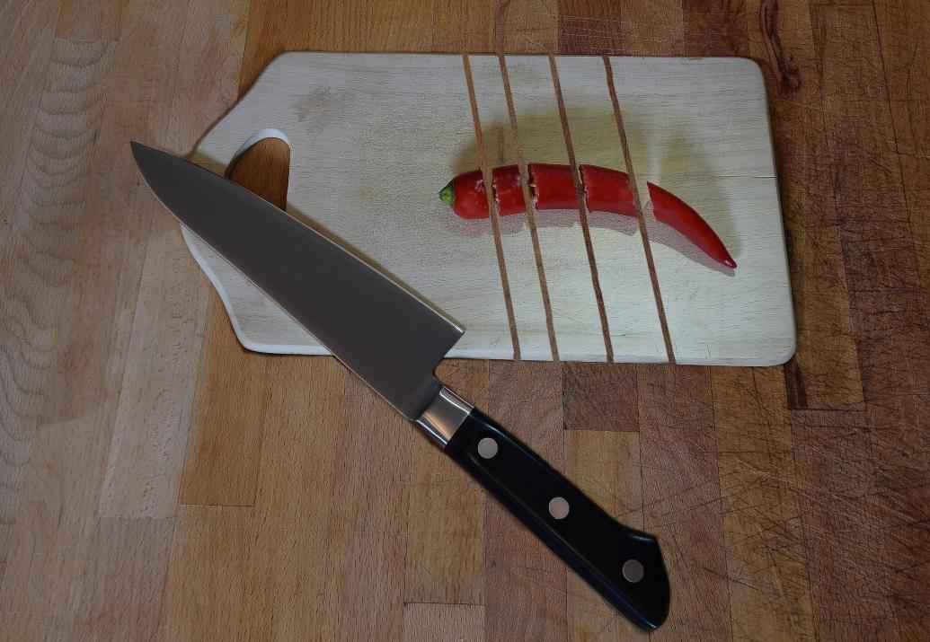 The design of a chef knife besides a wooden cutting board