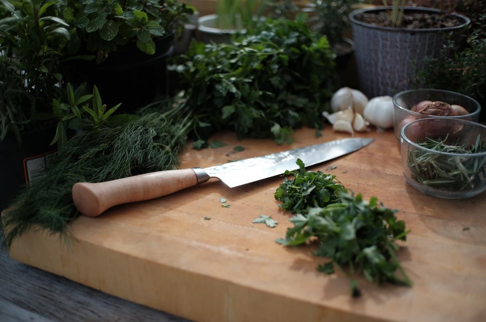 Knife with wooden handle on a cutting board with veggies