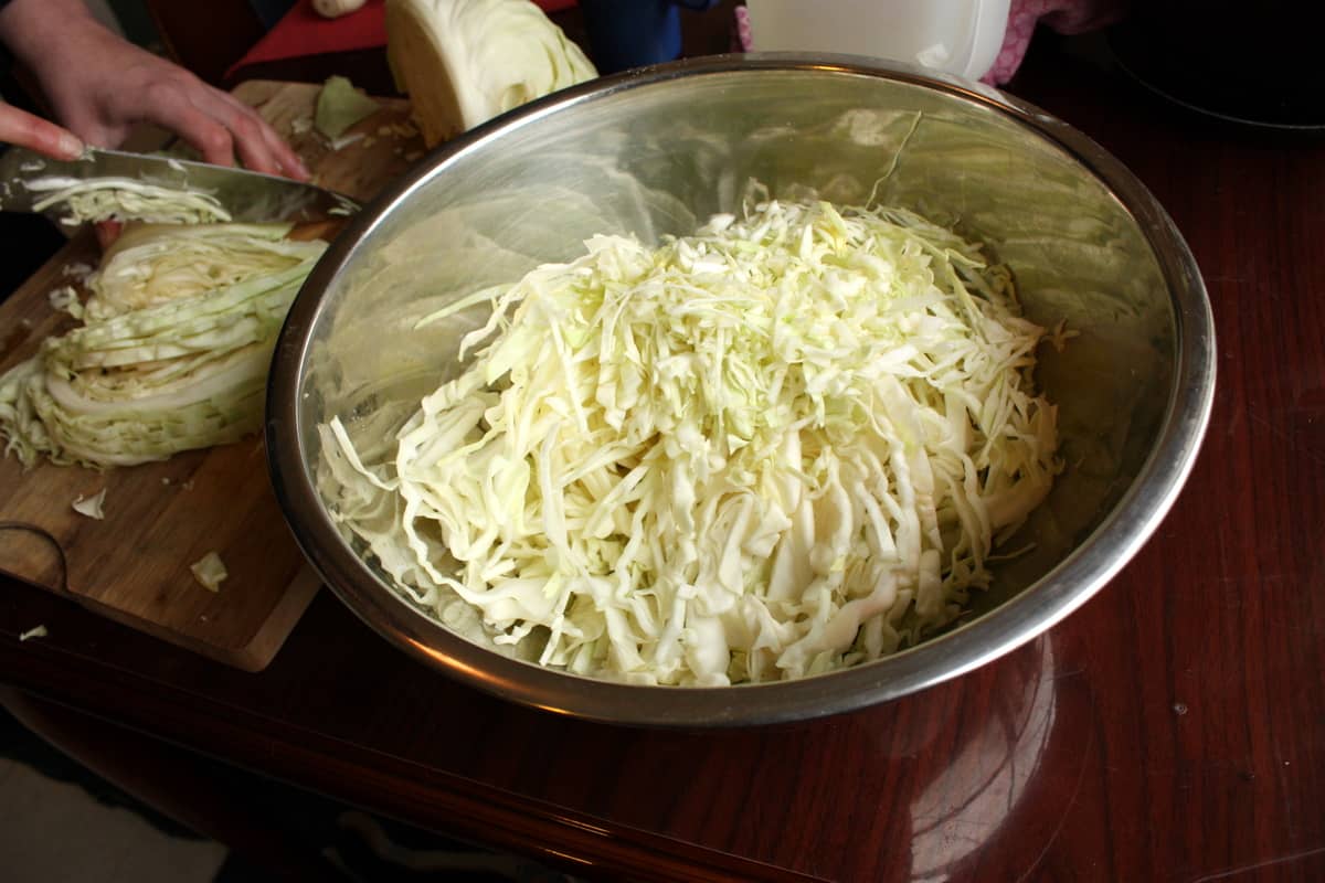 A cook slicing cabbage on a wooden cutting board
